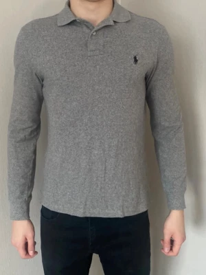 Snygg grå långärmad piké från Ralph Lauren - Sjukt snygg klassisk grå långärmad piké från Ralph Lauren med svart logga på bröstet. Slim fit, enkel och stilren design som passar till allt! Nytvättad såklart och kan strykas vid önskemål. Postar inom 24h📦 köp mer än ett plagg för 10% rabatt🤝 Tveka inte på att höra av er vid funderingar!
