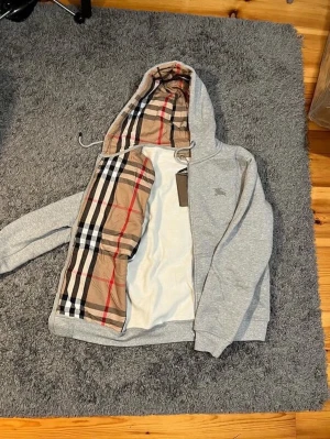 Burberry Zip-hoodie - Helt ny och oanvänd Burberry zip-hoodie. 10/10 skick. Riktigt fin och bekväm. Det är storlek M, men passar nog också S. Rekommenderar starkt!