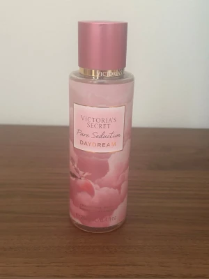 Victoria's Secret Pure Seduction Daydream - Fräsch body mist från Victoria's Secret i doften Pure Seduction Daydream. Flaskan är rosa med guldiga detaljer och har ett drömskt mönster med persikotoner. Perfekt för dig som gillar söta och fruktiga dofter. Enbart testad enstaka gånger. 