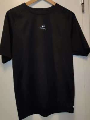 Svart tränings-tshirt från Pro Touch - Snygg svart tränings-tshirt från Pro Touch med DRY-PLUS-teknologi som transporterar bort fukt. T-shirten har rund hals, korta ärmar och diskret logga på bröstet. Perfekt för gymmet eller löprundan.