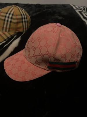 Rosa gucci keps - Säljer en rosa keps från Gucci med det klassiska GG-monogrammet över hela kepsen. På sidan finns en grön och röd randig detalj som ger extra lyxig känsla. Den är i helt nytt skick och endast prövad. Ställ gärna eventuella frågor eller prisförslag Mvh Clothez4you😊🤝