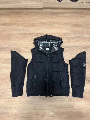 Burberry jacka/väst - Hej, säljer en burberry jacka som man kan göra till väst i storlek M passar perfekt till olika årstider har typ 2 jätte små hål på jackan där framme som man inte märker av för dom är så små och själva och som ni ser på sista bilden är den saken på luvan avklippt men går att sy till en tyg bit eller något sånt ananrs är allt som det ska vara.