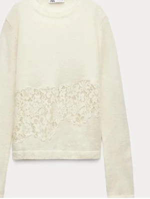 Säljer tröja med spets från Zara! - Supersöt vit stickad tröja från Zara med unik spetsdetalj i midjehöjd. Tröjan har rund halsringning, långa ärmar och en mjuk, skön känsla. Spetsen har blommigt mönster som ger en extra touch till looken. Perfekt för dig som gillar romantiska detaljer.