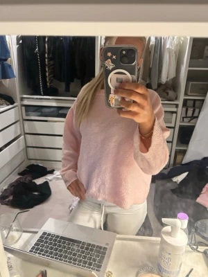 Ljusrosa fluffig stickad tröja - Mysig ljusrosa stickad tröja med avslappnad passform och långa ärmar. Tröjan har en enkel design utan synliga mönster och är gjord i ett fluffigt, mjukt material som känns skönt mot huden. Perfekt för att hålla värmen under kyliga dagar. Passar mig som har xs som på bilden 