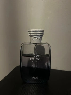 Hawas Ice For Him parfym - Snygg parfymflaska från Hawas, modellen Ice For Him. Flaskan är rektangulär med rundade kanter och har en mörkgrå toning. Locket är vitt med ett repmönster som ger en unik look. Text i vitt på framsidan. Perfekt för dig som gillar stilrena och moderna dofter.