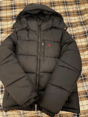Svart pufferjacka från Polo Ralph Lauren - Riktigt snygg Ralph Lauren pufferjacka för ett otroligt bra pris. Jackan är svart och har inga skador, skicket är 10/10 och är endast använd ett par enstaka gånger. Priset är purutat och klart!!