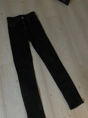 Svarta jeans med skits där nere  - Säljer ett par svarta jeans med slits nertill och klassisk femficksdesign. Jeansen har dragkedja och knapp framtill. Perfekta till en avslappnad streetstyle-look. Sitter så snyggt på!! 