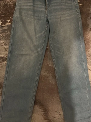 Ljusblå raka jeans från Levi's - Säljer ett par ljusblå jeans från Levi's med rak passform och klassiska fem fickor. Jeansen har en avslappnad look och är tillverkade i denim. Perfekta för dig som gillar en enkel och tidlös stil.