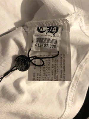 Vit t-shirt från Chrome Hearts - Snygg vit t-shirt från Chrome Hearts med klassisk logga och detaljer. Tillverkad i mjukt bomullsmaterial och har en stilren design. Perfekt för dig som gillar streetwear och exklusiva märken.