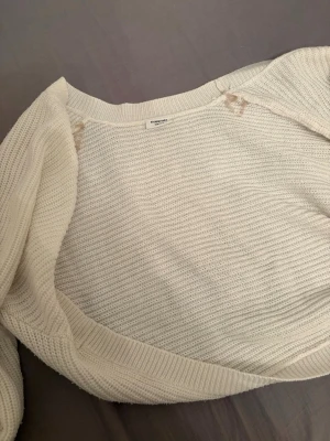 Vit stickad tröja från Kappahl - Klassisk vit stickad tröja från Kappahl med rund halsringning och ribbade muddar. Tröjan har en enkel, rak passform och är tillverkad i mjukt stickat material som passar perfekt till lager på lager. Enkel och stilren design.