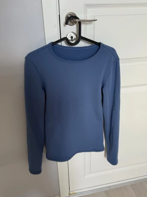 Blå fleece-tröja med rund hals - Mysig blå fleece-tröja med rund hals och långa ärmar. Tröjan har en enkel, stilren design utan tryck eller mönster och är tillverkad i mjukt fleecematerial som håller dig varm under kyliga dagar.