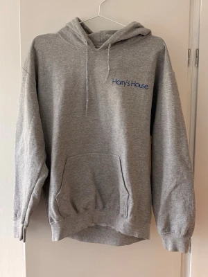 Grå Harry's House hoodie - Super fin Harry styles hoodie från Harrys house, önskar jag kunde ha men den är tyvärr för kort i ärmarna för mig :( den är köpt på Vinted men inte använd av mig, men använd sedan innan, är i storlek M🌸