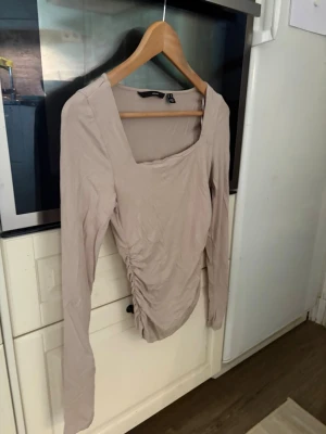 Beige långärmad topp med rynk - Trendig beige topp med långa ärmar och fyrkantig ringning. Toppen har snygg rynkdetalj på sidan som ger en cool och smickrande passform. Perfekt att styla med jeans eller kjol för en clean look. Använd fåtal gånger, inga defekter. Storlek xs. Priset går att diskutera, skicka gärna prisförslag🌸