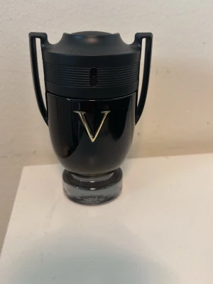 Paco Rabanne Invictus Victory Extrẽme - Snygg parfymflaska från Paco Rabanne i svart glas med guldfärgat V på framsidan. Flaskan har en unik pokalform med två handtag och genomskinlig botten. Perfekt för dig som gillar exklusiva och moderna dofter.  Använt max 5 ML av parfymen. 