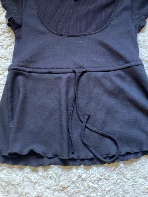 Svart Babydoll Topp med knyt från Nelly - Kmr aldrig till användning o är i princip i nytt skick förutom att den har samlat på sig lite damm/hår från min garderob.
