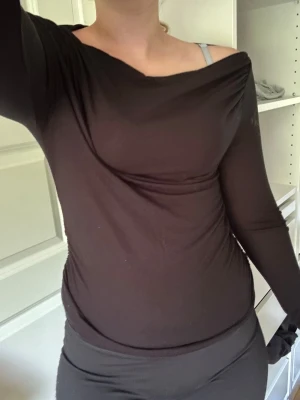 Svart långärmad topp med båtringning - Säljer en svart långärmad topp med snygg båtringning och tight passform. Perfekt att styla med både jeans och kjol för en clean look. Tunn och stretchig i materialet, vilket gör den superbekväm och enkel att bära.