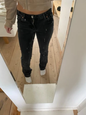 Svarta raka jeans med vintage-look - Säljer ett par svarta jeans med rak passform. Jeansen har en lätt tvättad vintage-look med subtila slitningar och klassiska fem fickor. Perfekta för en avslappnad och trendig stil.