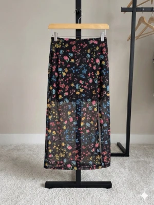 Blommig långkjol från H&M - Säljer en svart långkjol från H&M med färgglatt blommönster i rosa, blått och gult. Kjolen är i ett lätt och luftigt material. Storlek XS