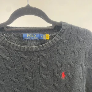 Svart kabelstickad tröja Polo Ralph Lauren - En svart kabelskornas tröja från Ralph lauren, säljer då jag tyvärr vuxit ur den, skulle säga att den sitter mer som M/S. Köpt på NK i Göteborg  riktigt fräsch o ha till sommarkvällarna! 