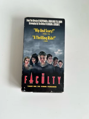 ”The Faculty” på VHS - kultklassiker! - VHS-utgåva av episka kultfilmen ”The Faculty” om när en eleverna på en high school börjar misstänka att deras lärare är utomjordingar. Bästa blandningen av skräck, sci-fi, komedi och tonårs-angst du kommer se i år! Regisserad av Robert Rodriguez, med skådespelare som Elijah Wood, Josh Hartnett och Jordana Brewster. Speltid: 104 minuter. Toppen, haha!