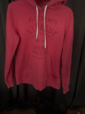 Rosa hoodie med tryck och huva - Snygg rosa hoodie från hm med tryck framtill och stor känguruficka. Hoodien har vit dragsko i huvan och ribbade muddar vid ärmslut och nederkant. 