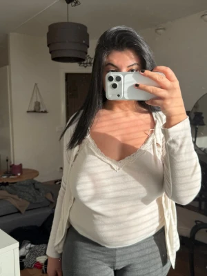 Vit ribbad linnetopp med spetskant - Snygg vit ribbad linnetopp med v-ringning och spetskant upptill. Toppen är ärmlös och har en feminin, enkel design som passar perfekt till jeans eller kjol. Materialet känns mjukt och stretchigt, vilket gör den bekväm att bära hela dagen.