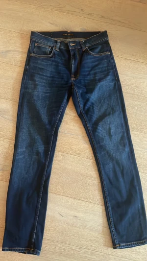 Mörkblå jeans från Nudie Jeans - Säljer ett par mörkblå jeans från Nudie Jeans med klassisk femficksmodell och raka ben. De har en ruggigt snygg fade wash. Modell Lean dean 31/30.