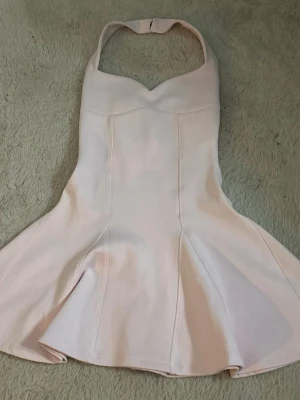 Ljusrosa halterneckklänning från Zara - slutsåld, supersnygg, ljusrosa, kort klänning från Zara med halterneck och markerad midja. Klänningen har en utsvängd nederdel och är ärmlös, perfekt för sommarens alla tillfällen. Materialet känns mjukt och har en lätt struktur. Storlek S