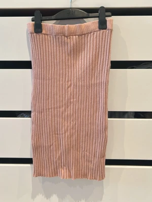 Ribbad beige kjol från BikBok - Säljer en ribbad beige kjol från BikBok i storlek M. Kjolen är midilång med en tight passform och har bred resår i midjan. Perfekt att styla med en enkel topp eller stickad tröja för en chill look.Lite nobrig på vissa ställen,men inget som märks mycket när den används.