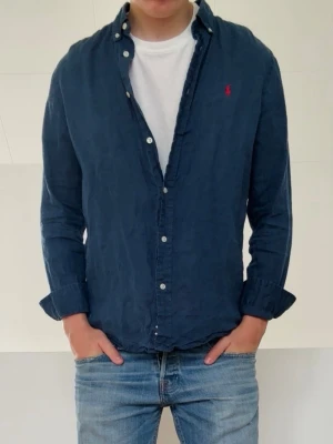 Mörkblå Ralph Lauren linneskjorta  - Mörkblå Ralph Lauren linneskjorta i strl 18-20 vilket motsvarar va strl S. Bra skick och och hör gärna av er vid frågor elr funderingar!!
