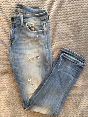 Jeans med slitningar - Säljer ett par ljusblå jeans från Levis med slitningar och hål på framsidan. Skick 8/10 inga defekter. 29/32. 