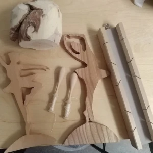 Träfigurer och snidade trädelar - Säljer ett set med handgjorda träfigurer i form av dansare, två snidade träben, en träkloss med naturligt mönster och en lång trälåda med spår. Perfekt för pyssel, dekoration eller hobbyprojekt. Alla delar är i ljust trä och har unika former.