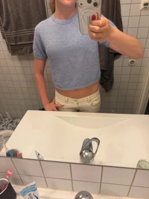 Ljusblå croppad stickad topp - Superfin ljusblå croppad topp med korta ärmar och rund hals. Stickad i mjukt material som känns skönt mot huden. Perfekt till jeans eller kjol för en avslappnad och trendig look.