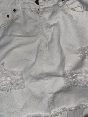 Snygg vit jeanskjol - Snygg vit jeanskjol med slitningar framtill. Ifrån Nly jeans. Storlek Xs. Inga defekter.