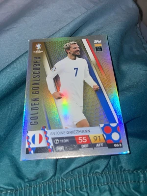 Antoine Griezmann samlarkort - Samlarkort med Antoine Griezmann från EM, holografisk yta och texten 'Golden Goalscorer'. Kortet har franska flaggan, spelarstatistik och siffror i rött och gult. Perfekt för dig som gillar fotboll och samlar på sportkort.