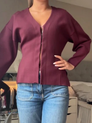 Vinröd kofta från Zara  - Stilren vinröd kofta med v-ringning och raka, långa ärmar. Koftan har en enkel, öppen design utan synliga knappar och är tillverkad i ett mjukt, slätt material. Slut i sortimentet