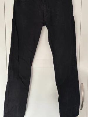 Svarta jeans från Levi's 511 - Säljer ett par svarta jeans från Levi's med klassisk femficksdesign och rak passform. Jeansen har Levi's röda etikett på bakfickan och är tillverkade i ett slitstarkt bomullsmaterial. Perfekta för en clean och stilren look. Storlek 32/34. Kommer från djur- och rökfritt hem