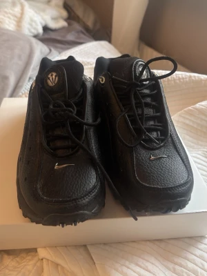 Svarta sneakers med silverdetaljer - Säljer ett par svarta sneakers med chunky sula och små silverfärgade detaljer. Skorna har en sportig look med perforerat läder och snörning. Passar perfekt för dig som gillar streetwear och vill ha något stilrent men ändå unikt.