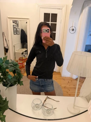 Svart långärmad träningstopp - Svart långärmad träningstopp  med halv dragkedja framtill och liten logga på bröstet. Tillverkad i stretchigt syntetmaterial som andas, perfekt för aktiva dagar. Snygg och enkel design som passar till mycket.