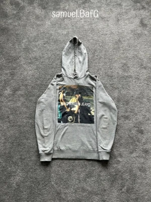 Calvin Klein Photo Print  - Säljer denna lite speciellare Calvin Klein Photo Print Hoodie i Grå. Storlek S. Gjord på 100% bomull och väldigt bekväm att ha på sig.