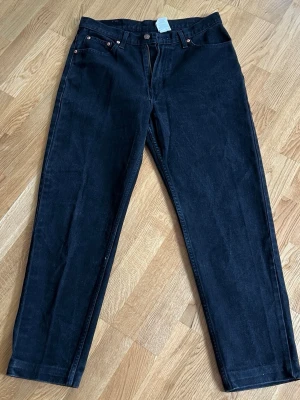 Svarta raka jeans från Jordache - Snygga svarta jeans från Jordache i rak modell. Tillverkade i 100% bomull för en klassisk jeanskänsla. Jeansen har fem fickor, bälteshällor och kopparfärgade nitar. Perfekta för dig som gillar tidlös och enkel stil.