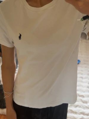 Vit t-shirt från Ralph Lauren - Klassisk vit t-shirt från Ralph Lauren med den ikoniska lilla loggan broderad på bröstet. T-shirten har rund halsringning och korta ärmar. Perfekt basic-plagg som funkar till allt och är gjord i mjuk bomull för skön känsla.