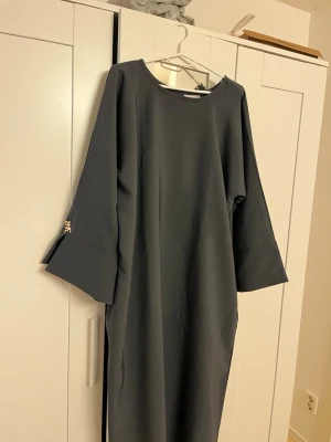 Grå abaya med fickor  - Grå abaya med fickor i strl 52, använd och knottrig som syns på bilderna lite överallt på abayan.