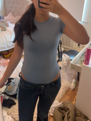 Ljusblå basic body med kort ärm - Säljer en enkel och stilren ljusblå body med korta ärmar och rund hals. Perfekt att styla med jeans eller kjol. Materialet ser ut att vara mjukt och stretchigt för en bekväm passform. Köpt för 300kr!