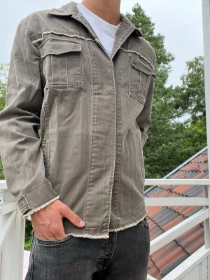 Overshirt - Otroligt snygg och unik overshirt från märket Soho New York. Olivgrön färg med osydda kanter. Riktigt feta detaljer som sömmarna och kragen. 