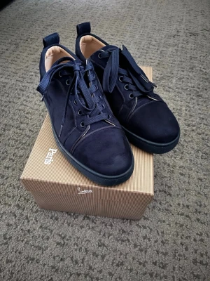 Mörkblå sneakers från Louboutin  - Säljer ett par Christian Louboutin sneakers. Använda men i fint skick. Det finns mindre bruksspår och skrapmärken på undersulan. Box medföljer. Storlek 41.