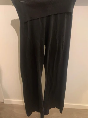 Svarta vida mjukisbyxor - Säljer ett par svarta mjukisbyxor med bred resår i midjan och raka, vida ben. Byxorna är gjorda i ett mjukt och stretchigt material som känns skönt mot huden. Perfekta för chill dagar eller när du vill ha det extra bekvämt. Är noppriga vid låren!