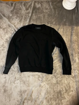 Svart sweatshirt från peak performance  - En stilren svart sweatshirt från peak performance med rund halsringning och ribbade muddar vid ärmslut och nederkant. Perfekt basic-plagg att matcha med jeans eller joggers. Tillverkad i mjukt material för skön komfort. Vid frågor hör av er priset kan alltid diskuteras 