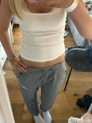 Gråa mjukisbyxor från Nike - Säljer ett par gråa mjukisbyxor från Nike med klassisk logga på vänster ben. Byxorna har resår i midjan och muddar vid bensluten samt två sidofickor. Perfekta för chill dagar eller träning. Mjukt och bekvämt material.