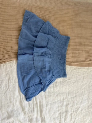 Jättefin blå kort volangkjol ifrån Gina Tricot  - Jättefin himmelsblå kort kjol med volanger ifrån märket Gina Young i storlek 158/164 som är i bra skick och perfekt nu till sommaren🌸Den är i bra material, har en fin passform och passar till allt🤍 Kjolen är unik, somrig och är i en superfin färg. Skriv om funderingar, lämna gärna omdöme och priset kan diskuteras😊